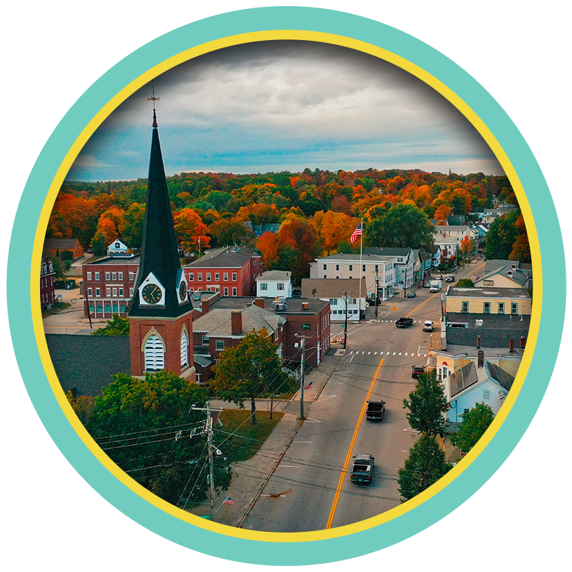 Aerial view of a small town with a church steeple and autumn trees in a circular frame.