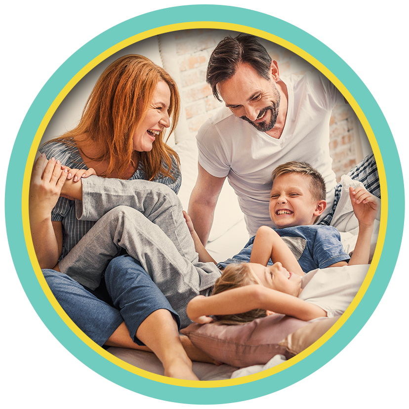 Smiling family sitting on a couch with a laughing child indoors