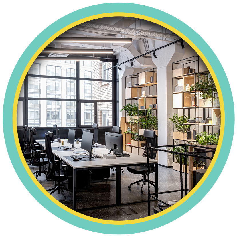 Modern office meeting room with desks, plants, and large windows, framed by a circular border